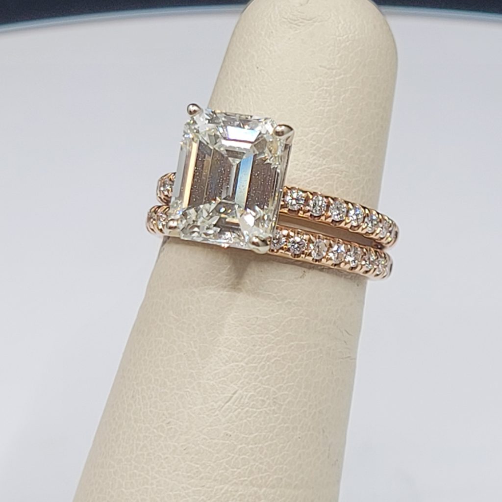 A ring with a rectangular center stone and matching bands on a white display stand.