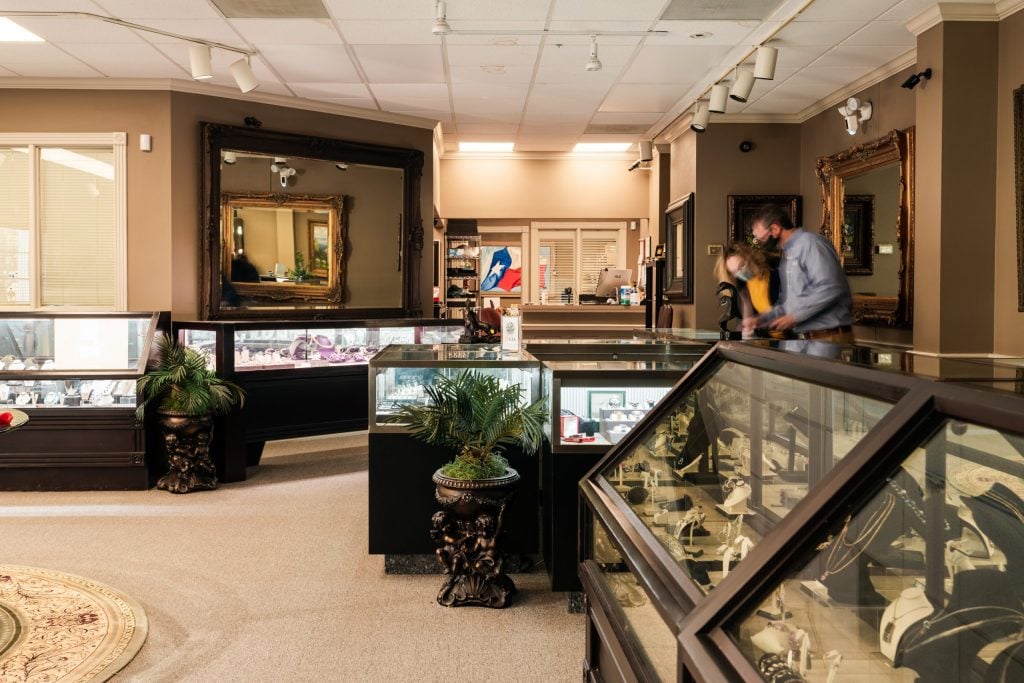 A wide interior view of the jewelry showroom with glass display cases and seating.