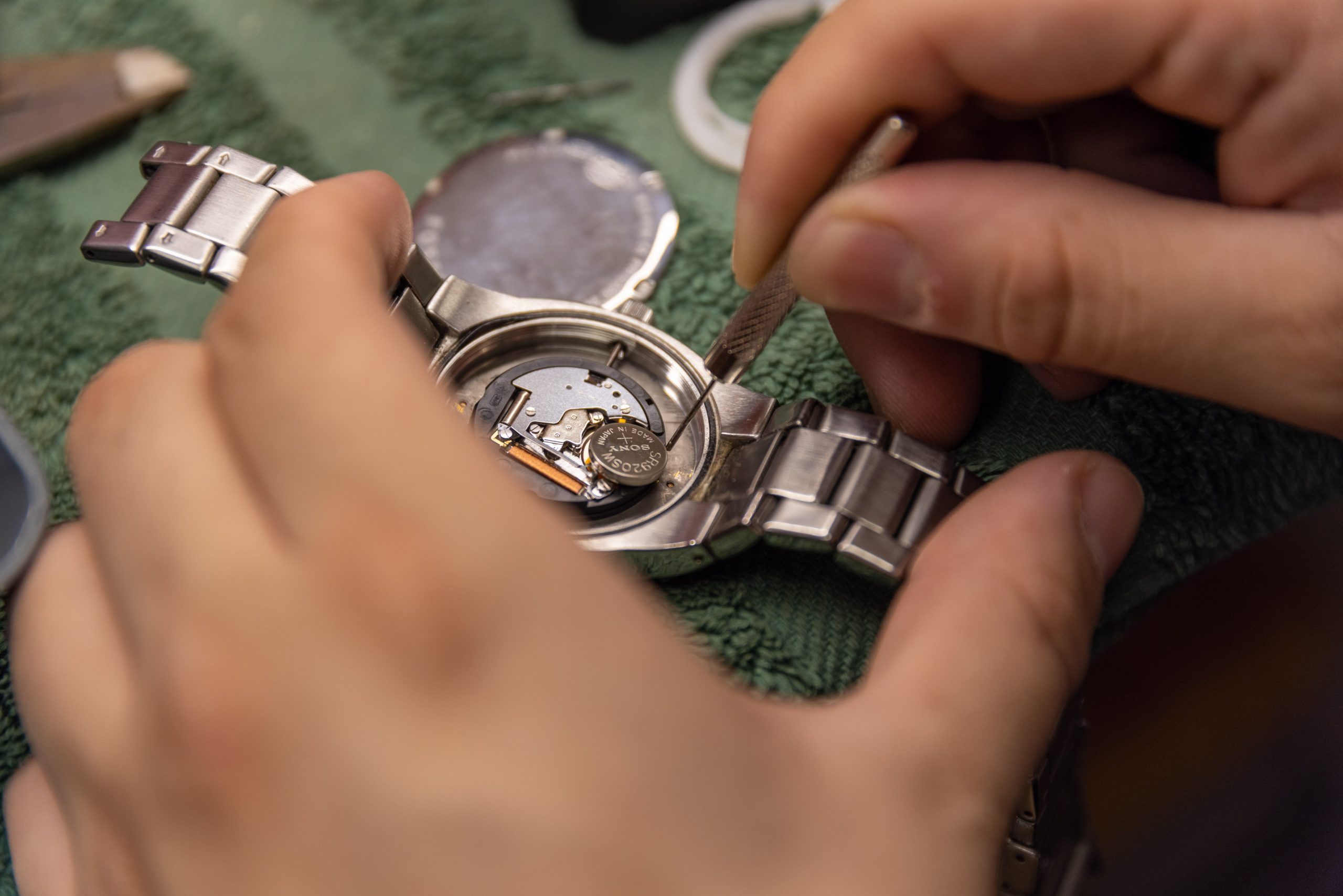 A jeweler inspects the movement of an open wristwatch.