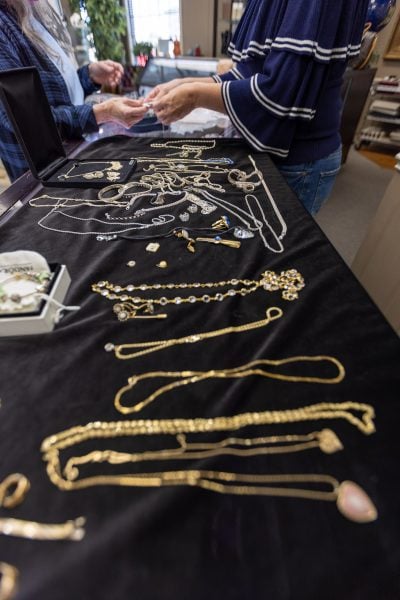 Jewelry being examined across a counter displaying necklaces and pendants in the showroom.