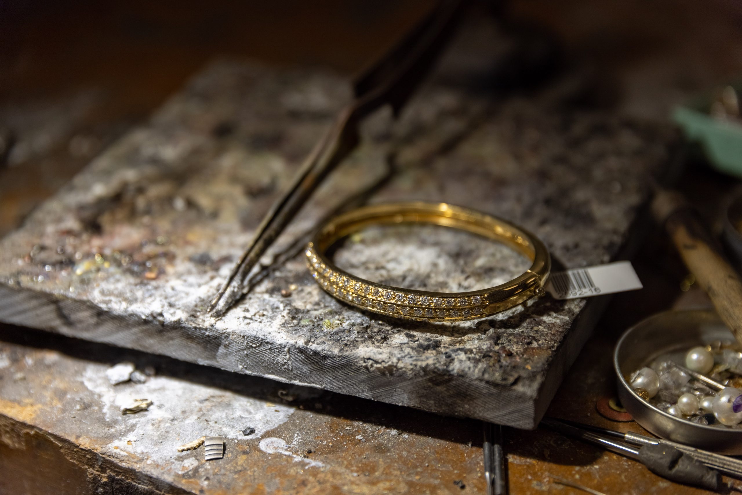 A ring held with metalworking tools at a jeweler’s workbench.