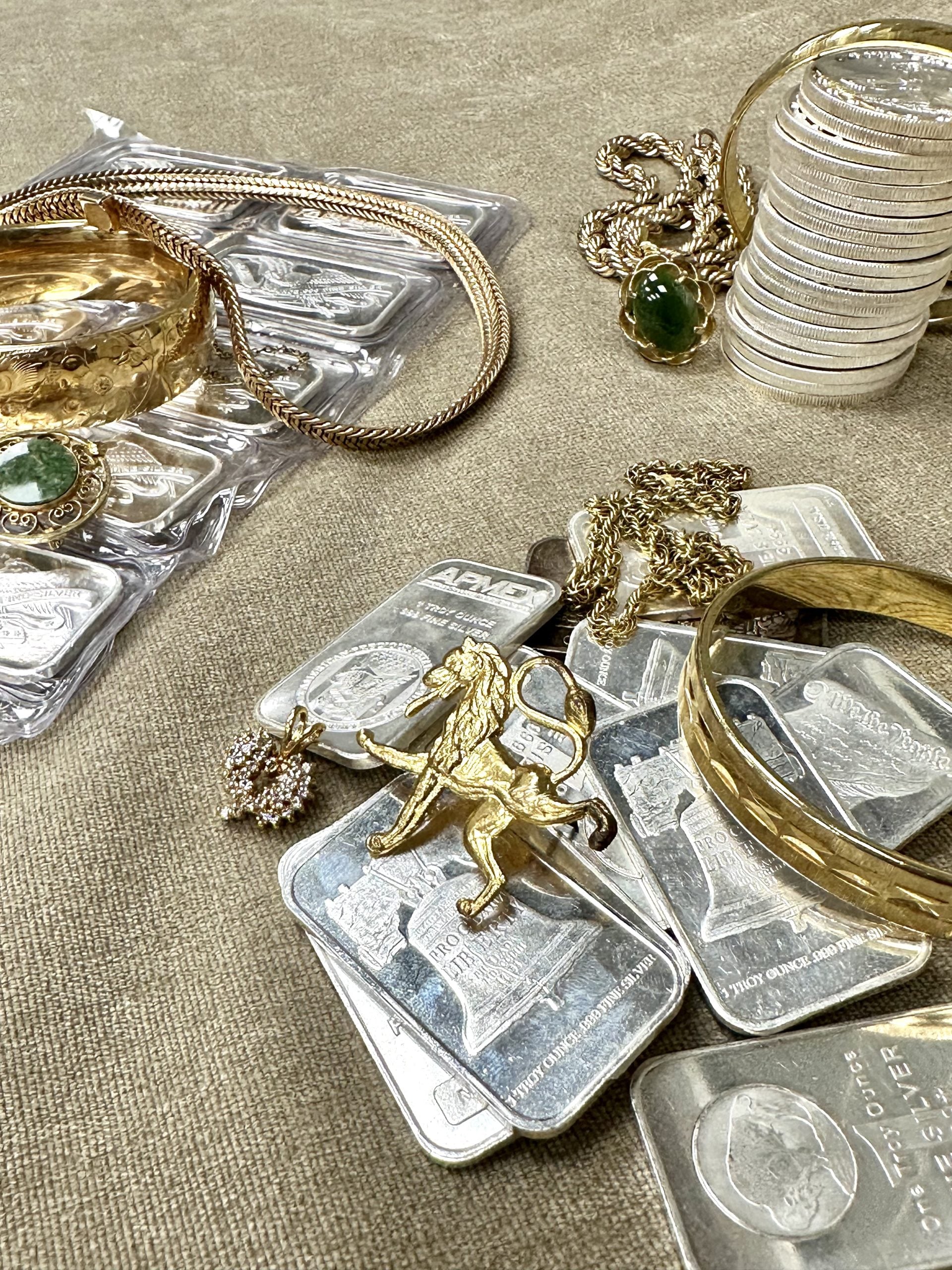 A collection of jewelry and silver-colored serving pieces arranged together.