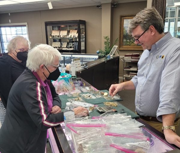 A team member talks with a customer across the jewelry showroom counter.