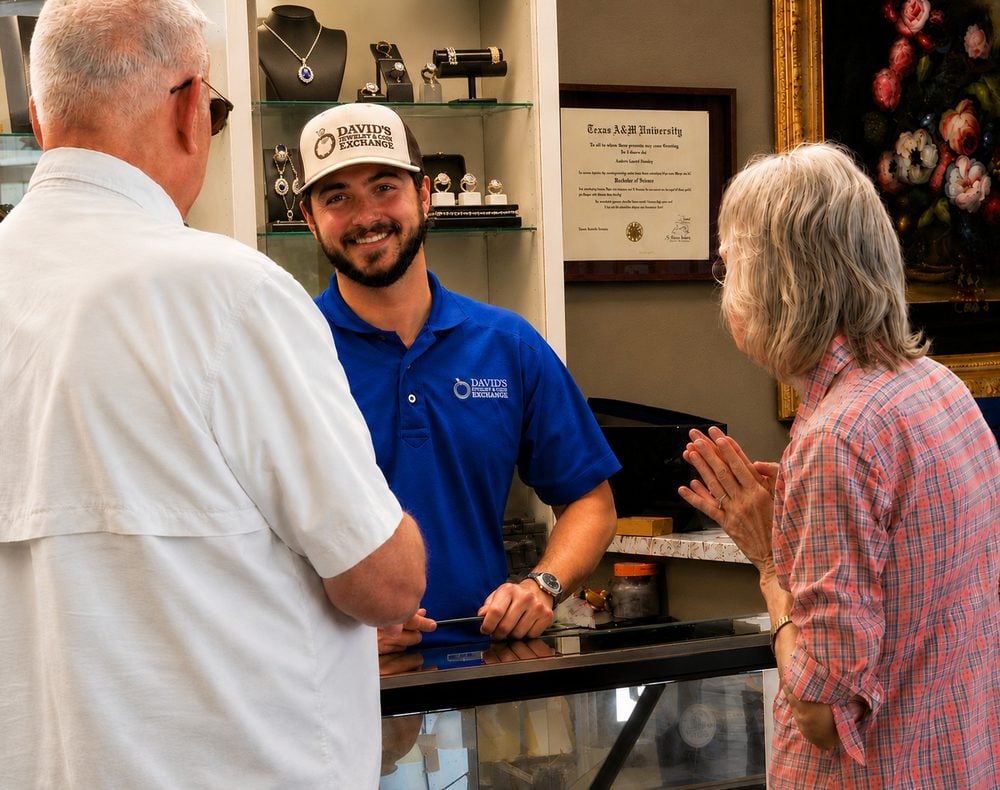 A team member talks with customers across the jewelry counter at David’s Jewelry & Coin Exchange.